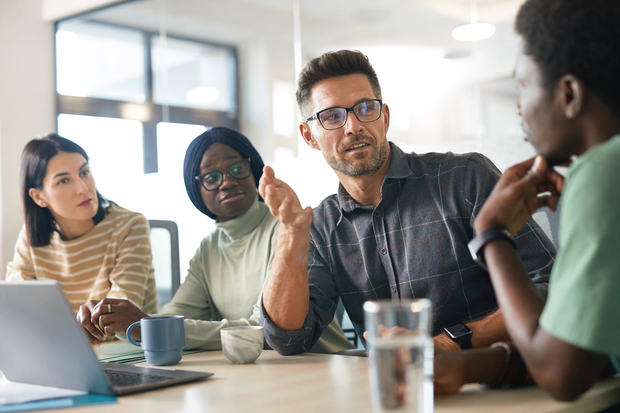 A diverse group of colleagues engaged in a collaborative discussion in a modern office setting.