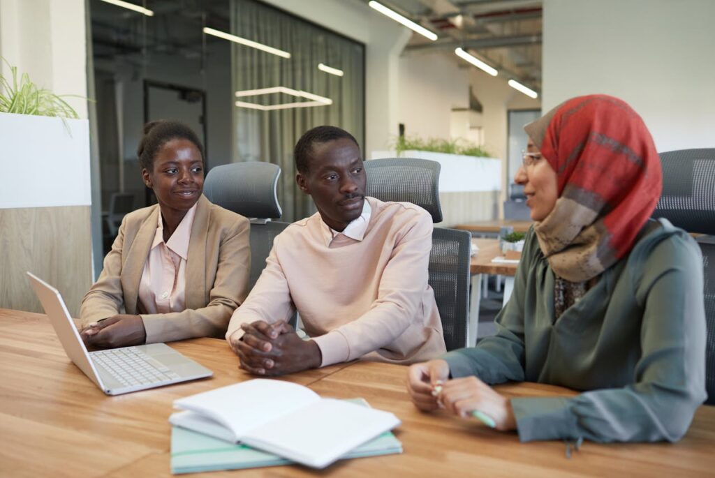 A diverse group of professionals engaged in a collaborative discussion around a wooden office table.